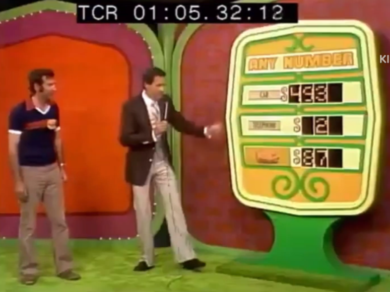 A scene from the game show 'The Price is Right', featuring the 'Any Number' pricing game. A host stands next to a large colorful board displaying prizes, including a car priced at 3, a smaller prize at , and a cash prize represented by a piggy bank at .