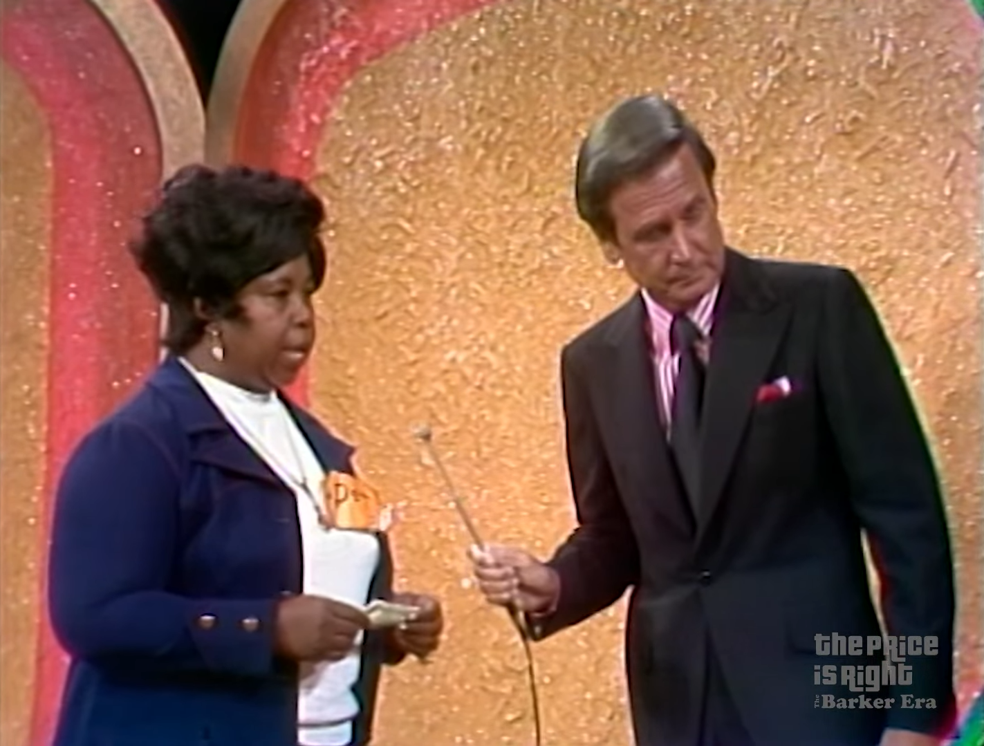 A contestant holding a dollar bill stands next to the host of a game show, both focused on the task at hand, with a glittery background.