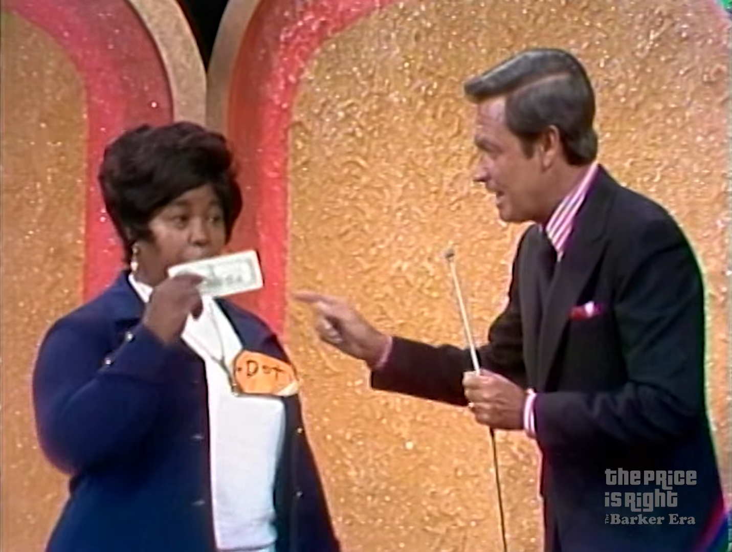 Contestant Doti holds up a 0 dollar bill while interacting with the host during The Price is Right game show.