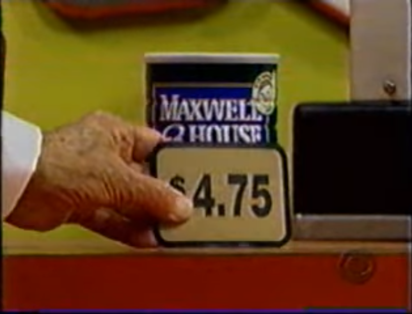 A hand holds a price tag displaying .75 next to a can of Maxwell House coffee.