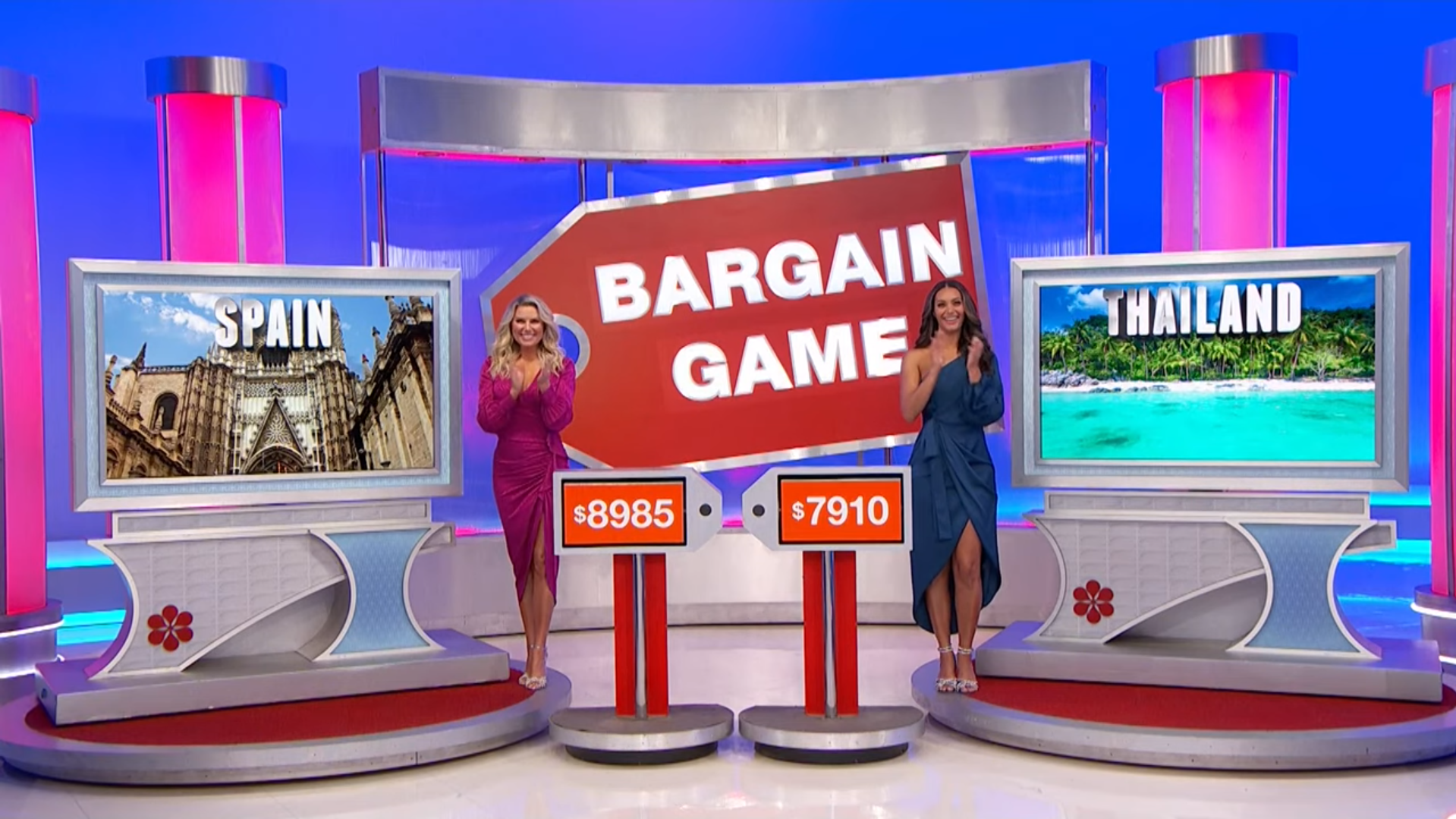 Two models stand next to displays for 'Bargain Game', featuring images of Spain and Thailand, with pricing tags of $8985 and $7910.