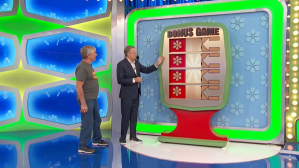 Drew Carey and a contestant standing next to a game board labeled 'BONUS GAME' on the set of The Price is Right, with colorful background elements.