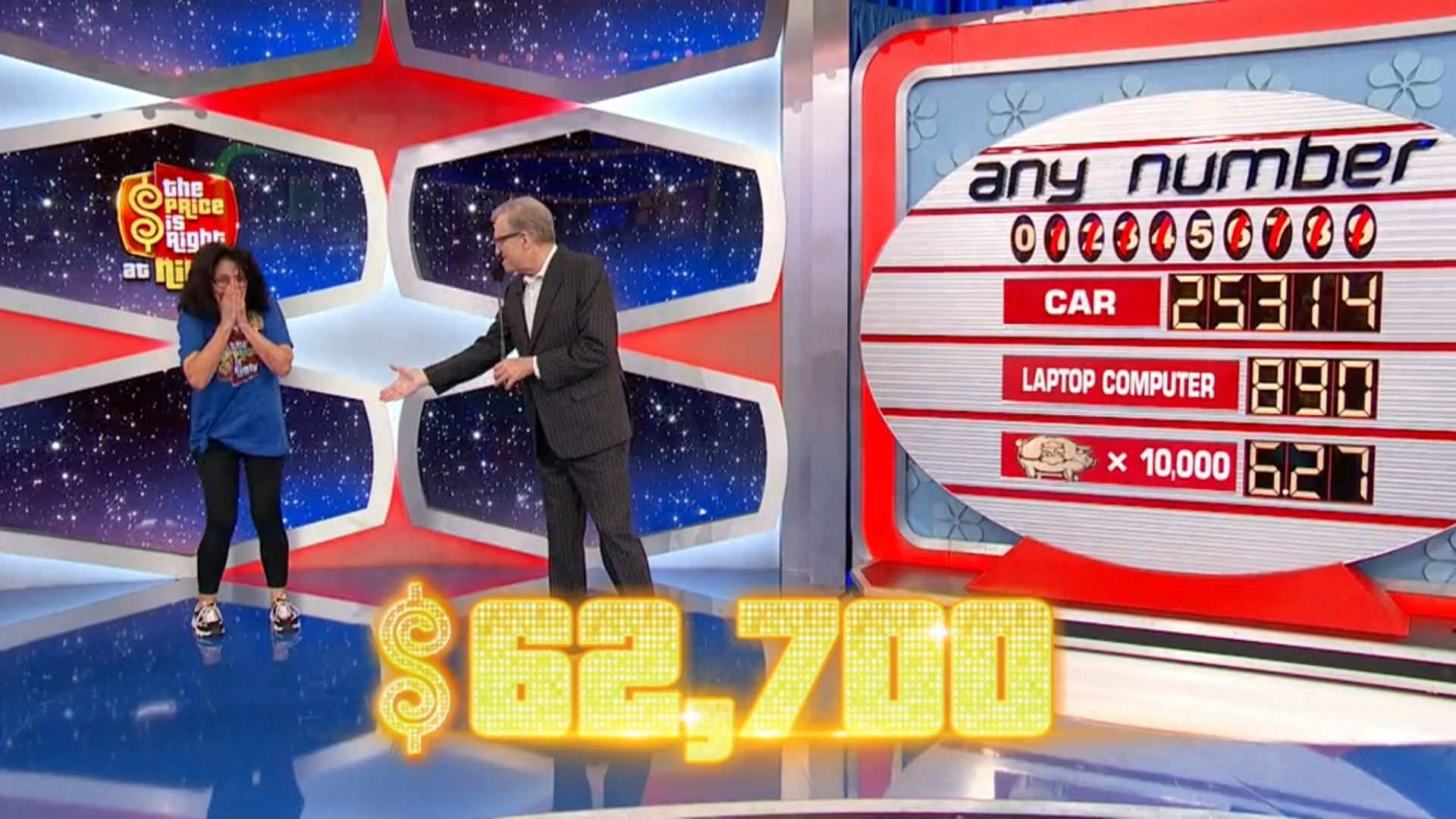 A contestant on 'The Price is Right' stands excitedly while the host gestures towards the prize board, featuring a car, a laptop computer, and a piggy bank with their respective values.