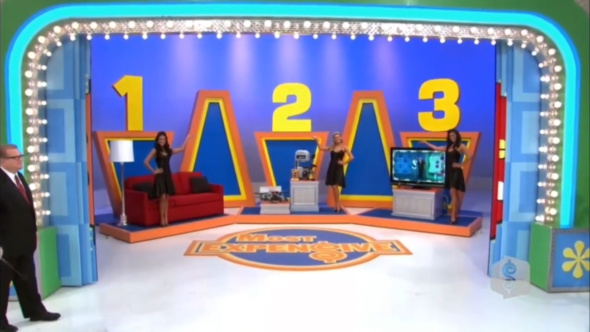 Contestants showcase three prize options in the game 'Most Expensive', with numbered displays and a host presenting.