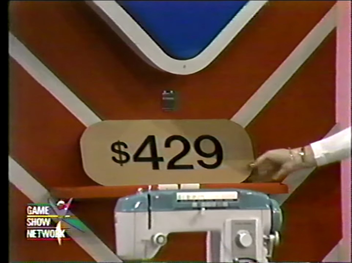 9 price tag displayed near a sewing machine in a game show setting.