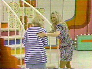 A contestant on The Price is Right approaches the Plinko board while a model helps them up the stairs.