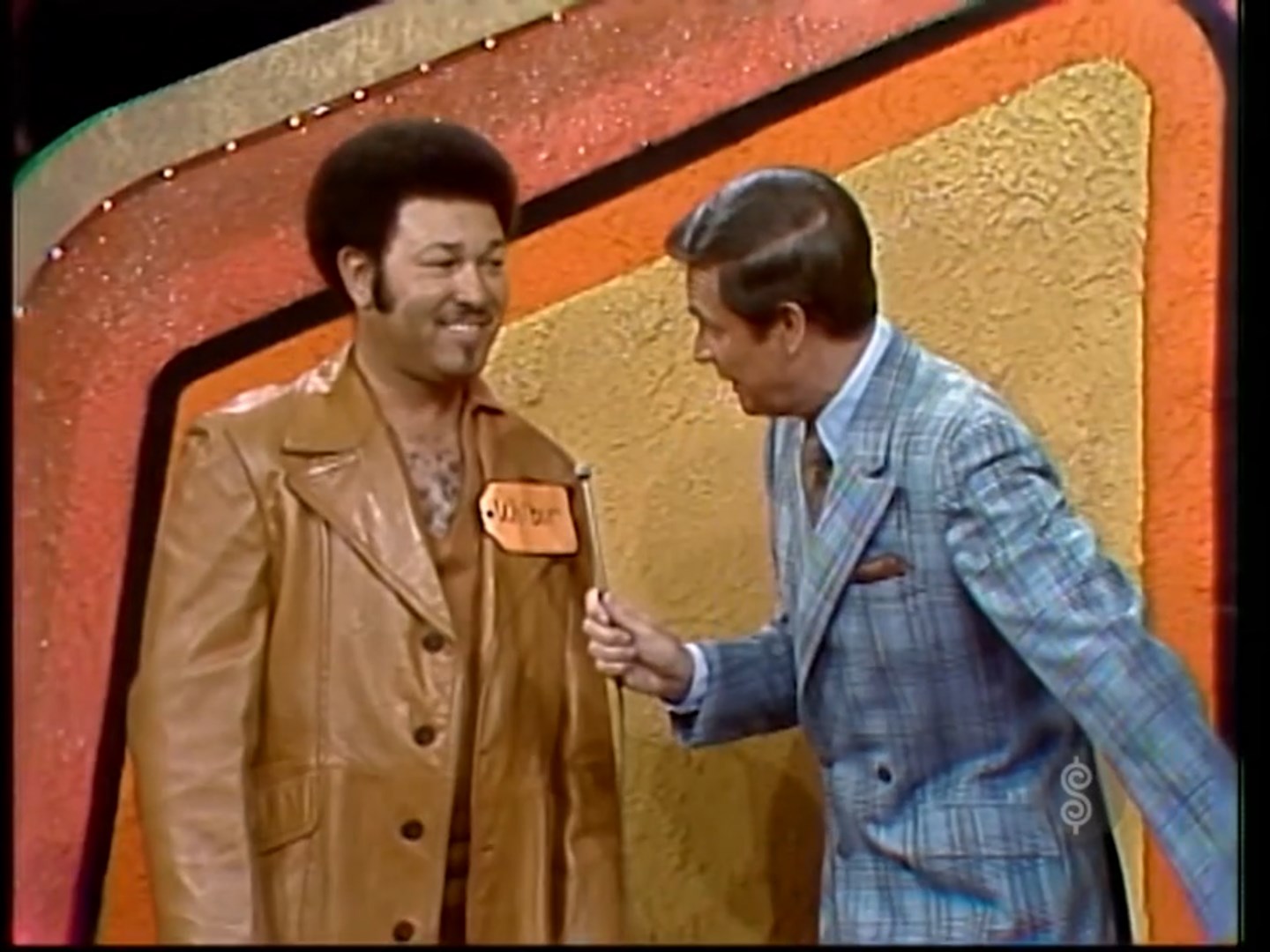 Contestant Wilbur smiles while talking to the host on stage during the game show 'The Price is Right', featuring colorful background.