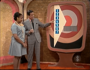 Bob Barker and a contestant stand next to a large game board featuring a dartboard design 'Bullseye' on 'The Price is Right' set in 1972.