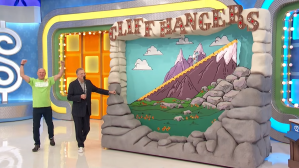 Drew Carey and a contestant are next to a large colorful game display titled 'Cliff Hangers,' featuring mountains and a sliding character on a path.
