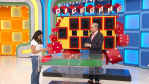 A contestant prepares to roll dice on the 'Dice Game' on The Price is Right, while Drew Carey stands nearby, with bright colorful walls and game elements in the background.