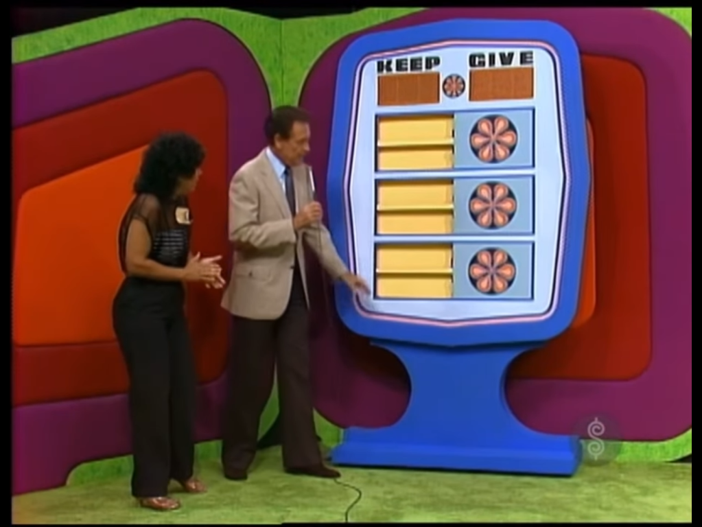 Contestants interacting with the pricing game 'Give or Keep' on The Price is Right, featuring options to "KEEP" or "GIVE" with game pieces visible.
