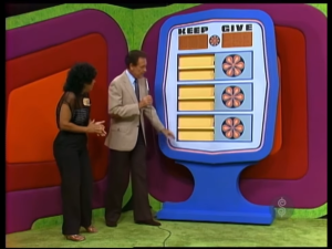 Contestants interacting with the pricing game 'Give or Keep' on The Price is Right, featuring options to "KEEP" or "GIVE" with game pieces visible.