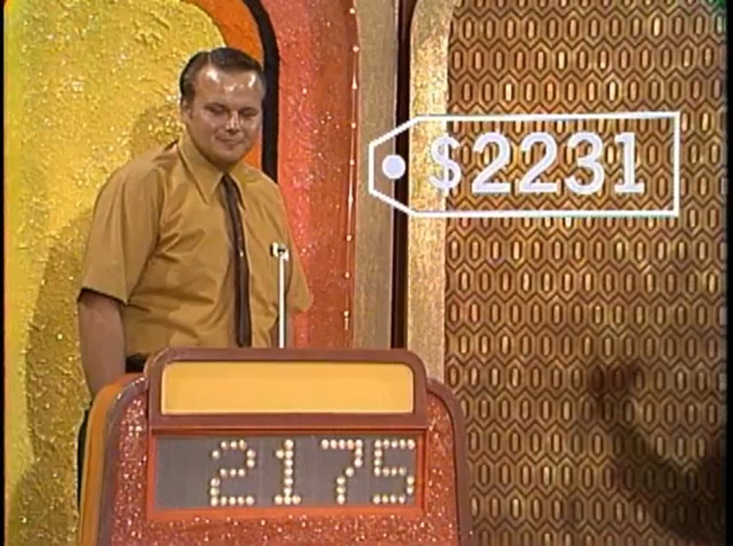 A contestant in a game show stands beside a podium displaying their bid of 75, while a price tag with the actual price of 31 is shown on the screen.
