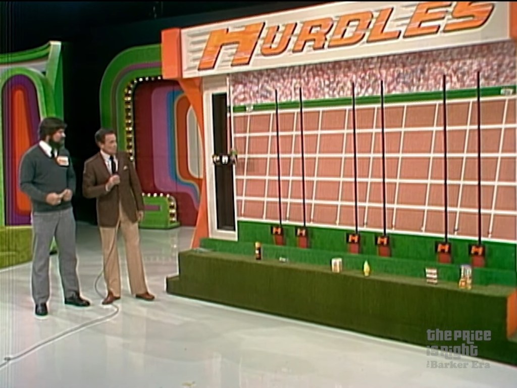 A scene from the game show 'The Price is Right,' featuring two contestants and the host in front of the 'Hurdles' pricing game display.