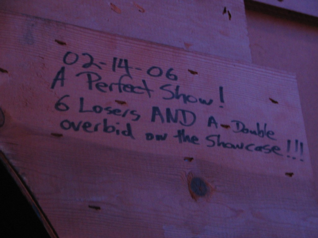 A wooden board with handwritten text dated 02-14-06, noting 'A Perfect Show!' and mentioning '6 Losers AND A Double overbid on the showcase!!!'.