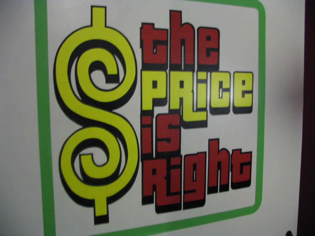 A colorful wall sign displaying the words 'the Price is Right' with a dollar sign symbol, prominently featuring yellow, red, and black lettering.