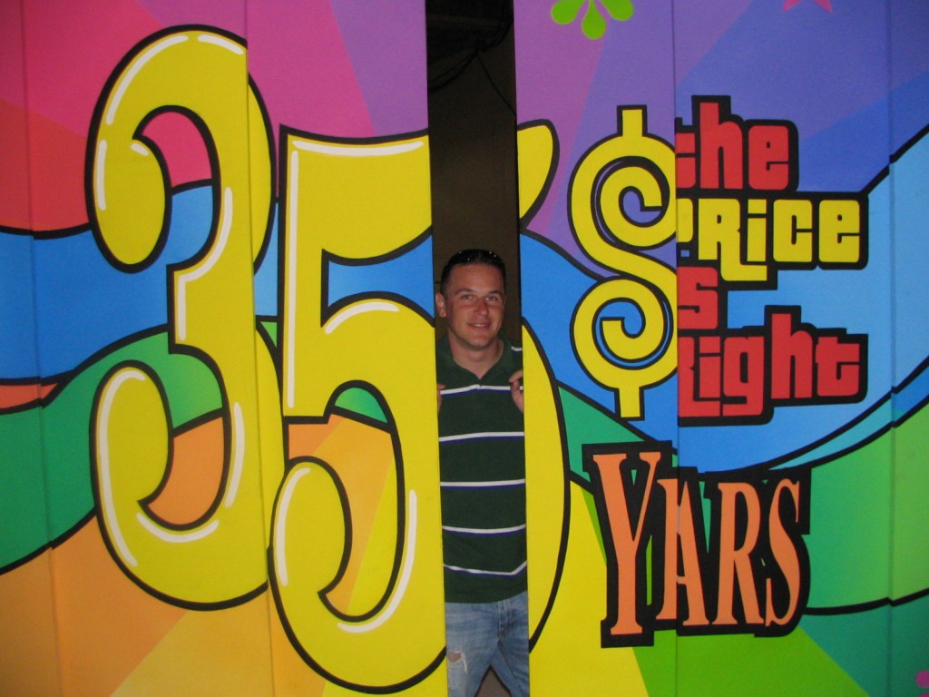A man stands between colorful panels celebrating 'The Price Is Right' 35th anniversary, featuring bold graphics and vibrant colors.