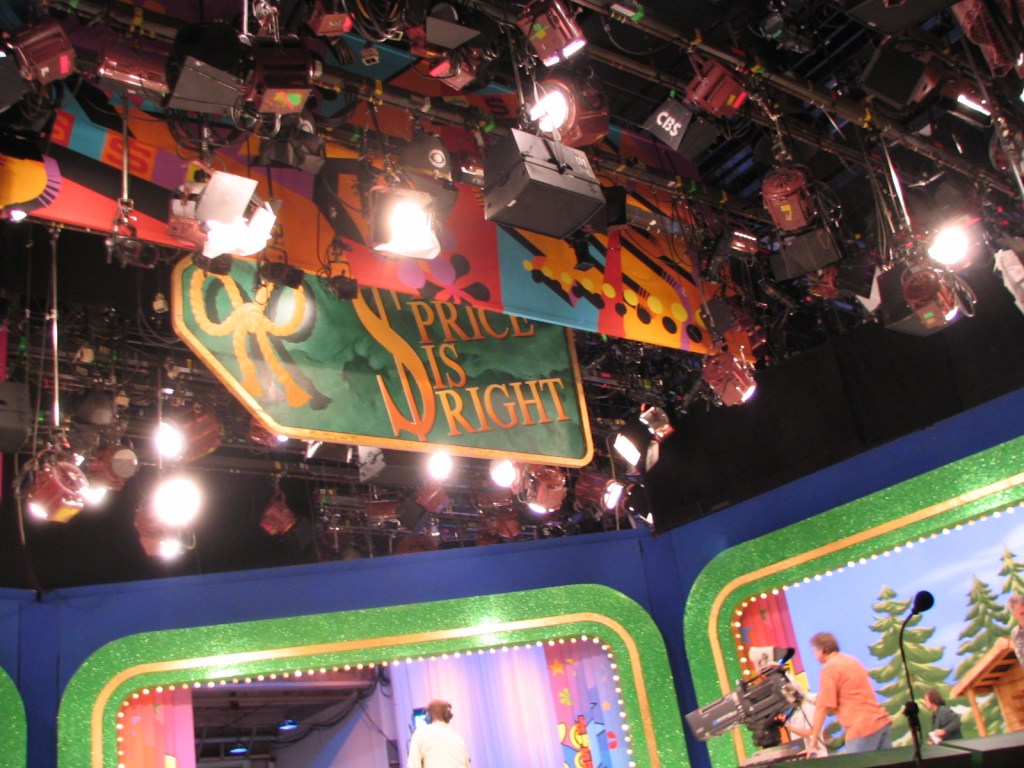 The stage of 'The Price is Right' show, featuring colorful decorations, lighting equipment, and the show's iconic logo hanging above.