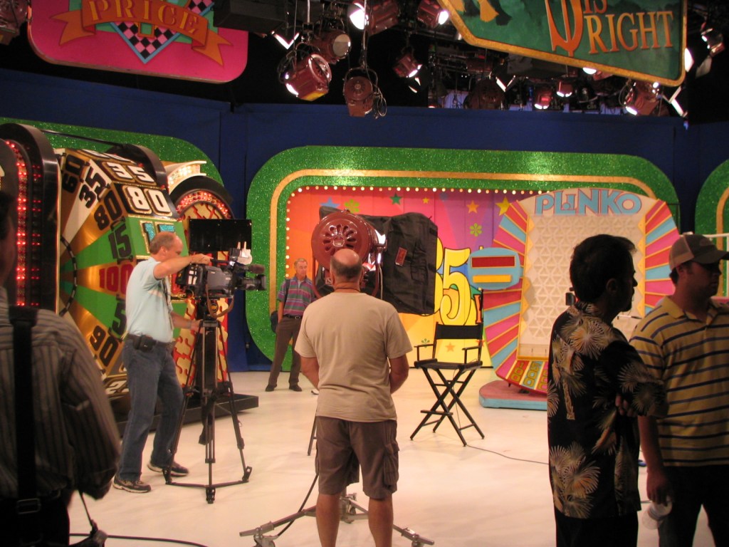Behind the scenes at the set of The Price Is Right, featuring the Plinko game area, camera crew, and crew members preparing for a taping.