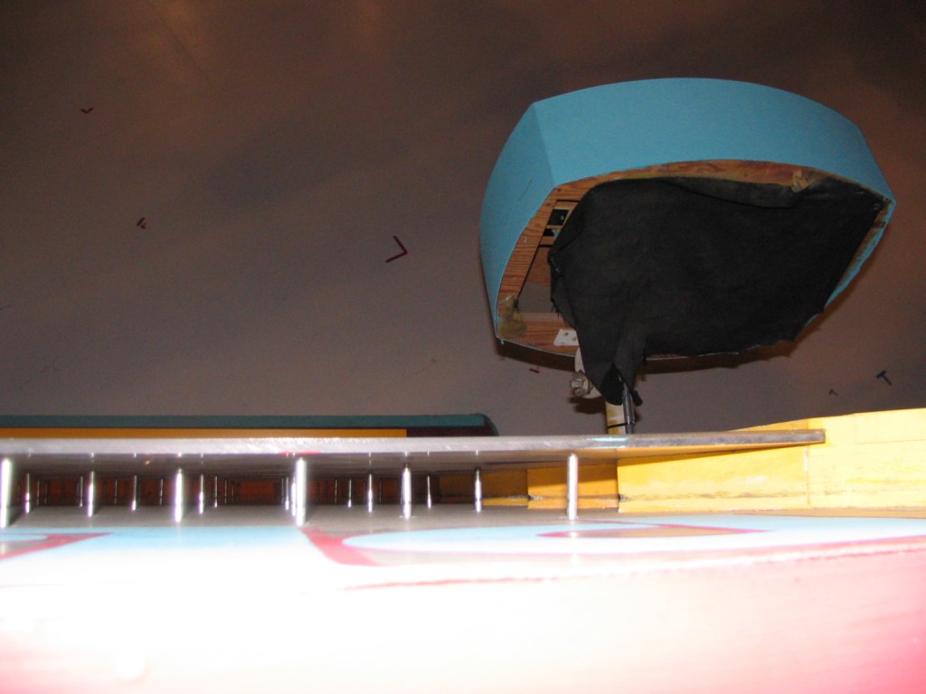 View of a backstage area with a blue structure overhead and a surface in the foreground, possibly a set piece.