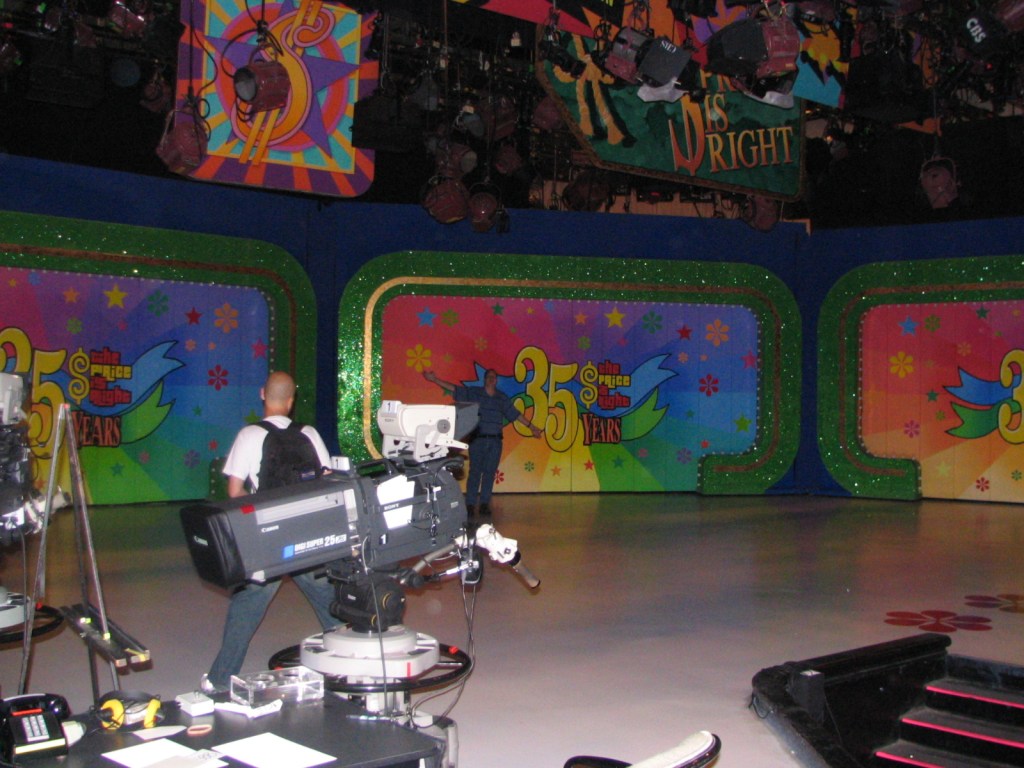 Backstage setup for the 35th season of The Price Is Right, featuring colorful decor and cameras in the foreground.