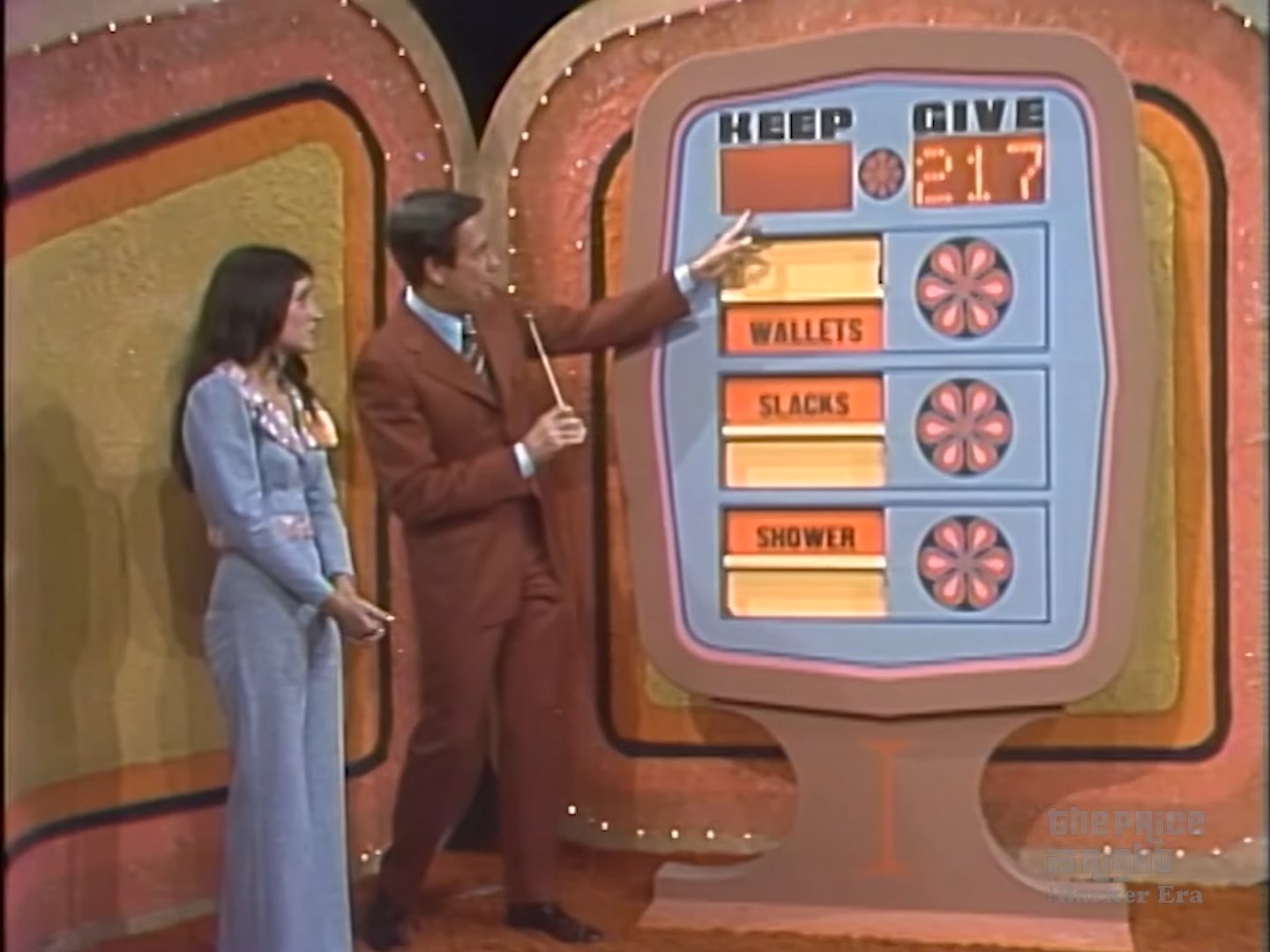 A game board for 'Give or Keep' showcasing a contestant with two columns titled 'KEEP' and 'GIVE' with a display of prizes including wallets, slacks, and a shower.