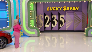 Contestant participating in the Lucky Seven game on The Price is Right, with a display showing the number $235 and the game's title prominently featured.