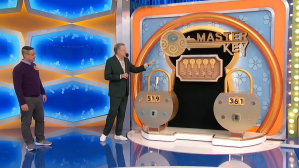 A game show host presenting the Master Key game, featuring two large locks on stage, with an audience member standing beside him on The Price is Right.