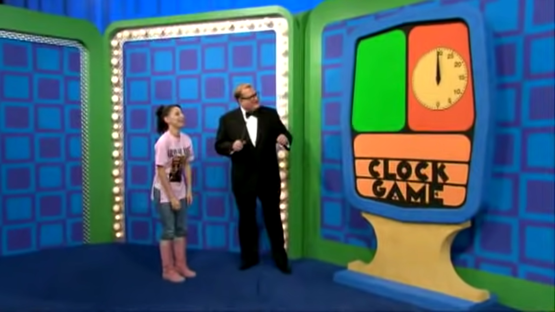 Cynthia and Drew Carey stand in front of the 'Clock Game' display, which features a large clock and colorful panels.