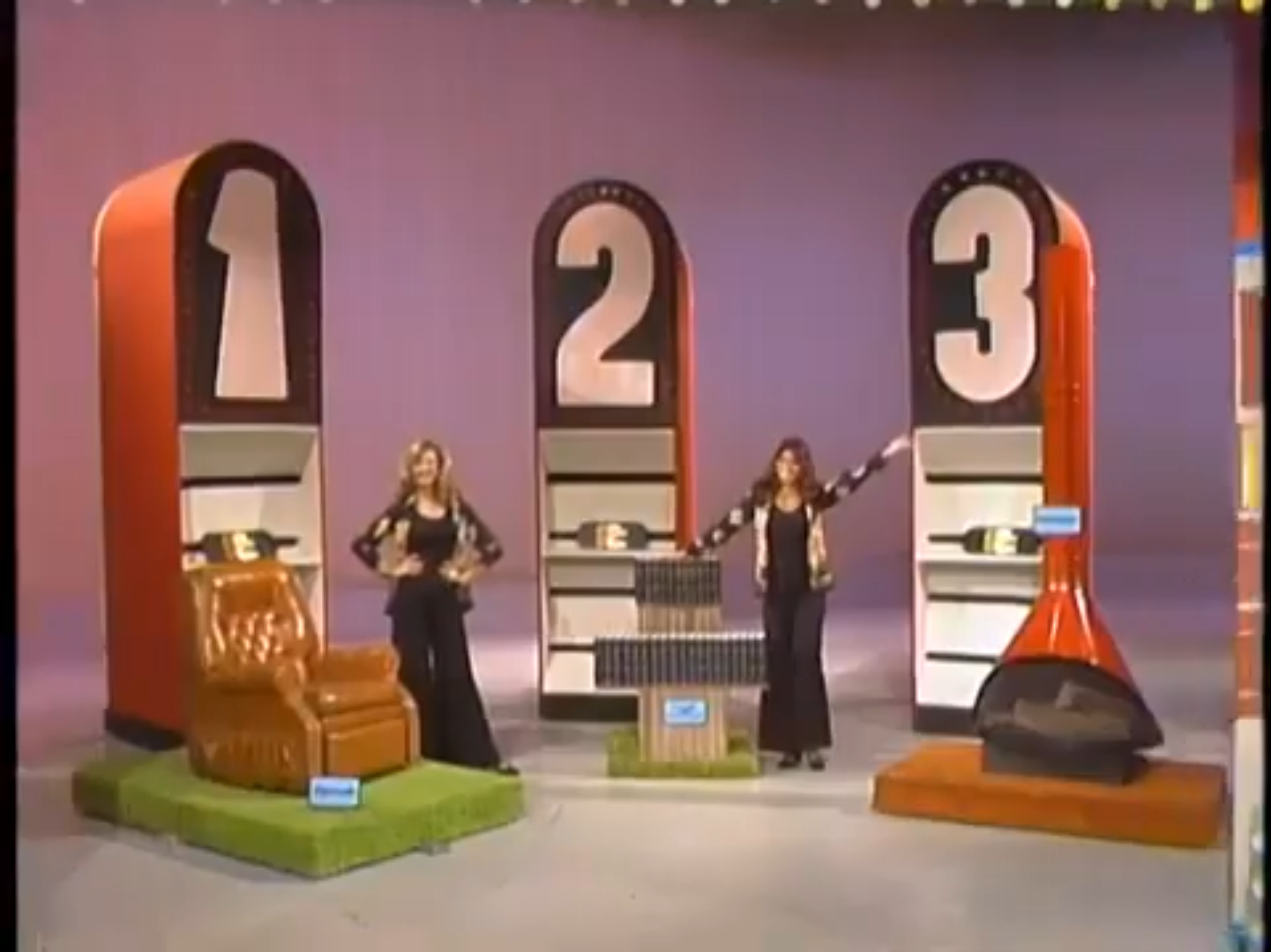 Contestants stand beside three prize podiums labeled 1, 2, and 3 during the game 'Most Expensive' on a colorful set.