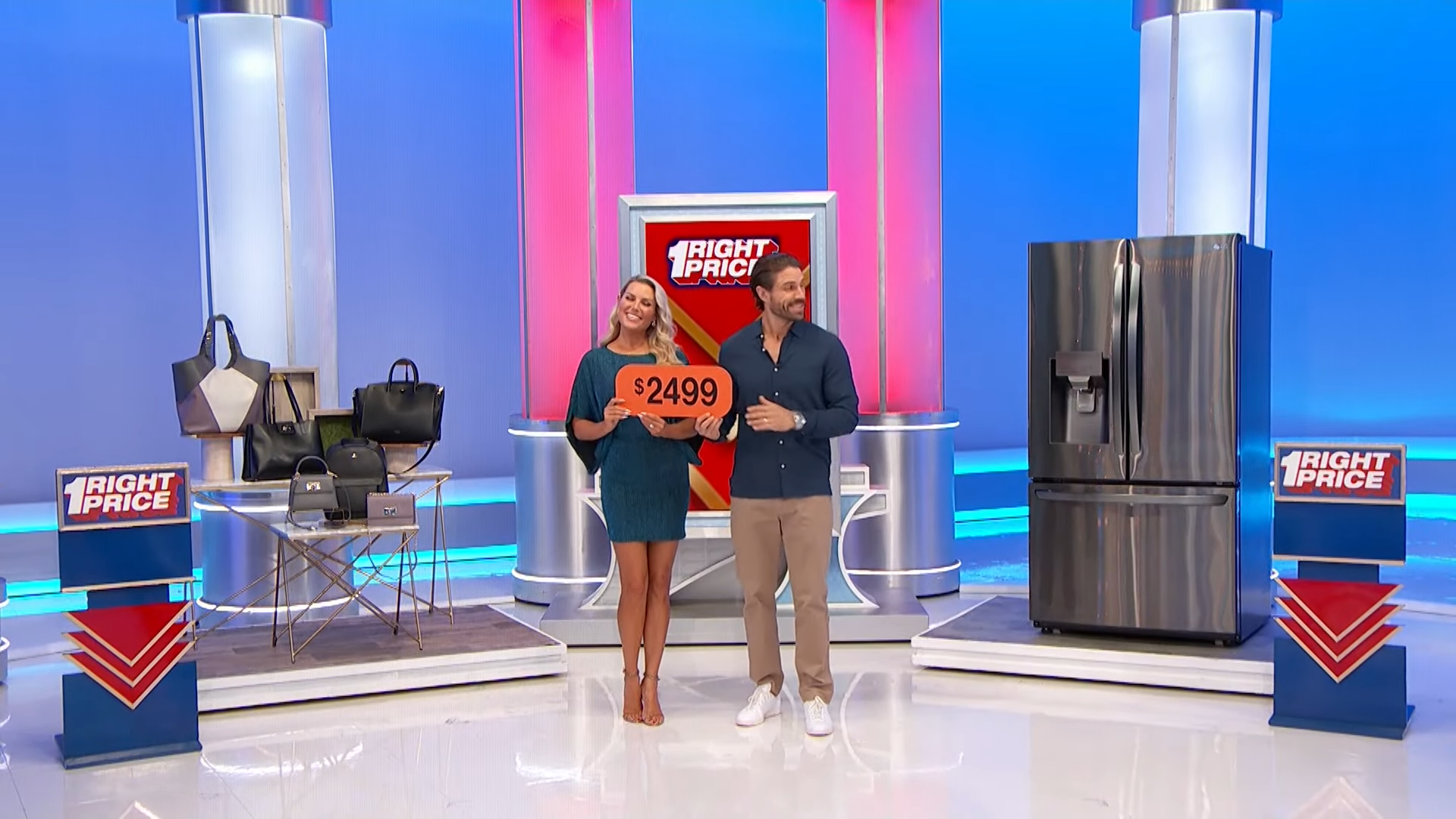 Two models stand beside a refrigerator, holding a sign with the price of $2499. Various handbags are displayed on a table nearby, with the One Right Price logo in the background.
