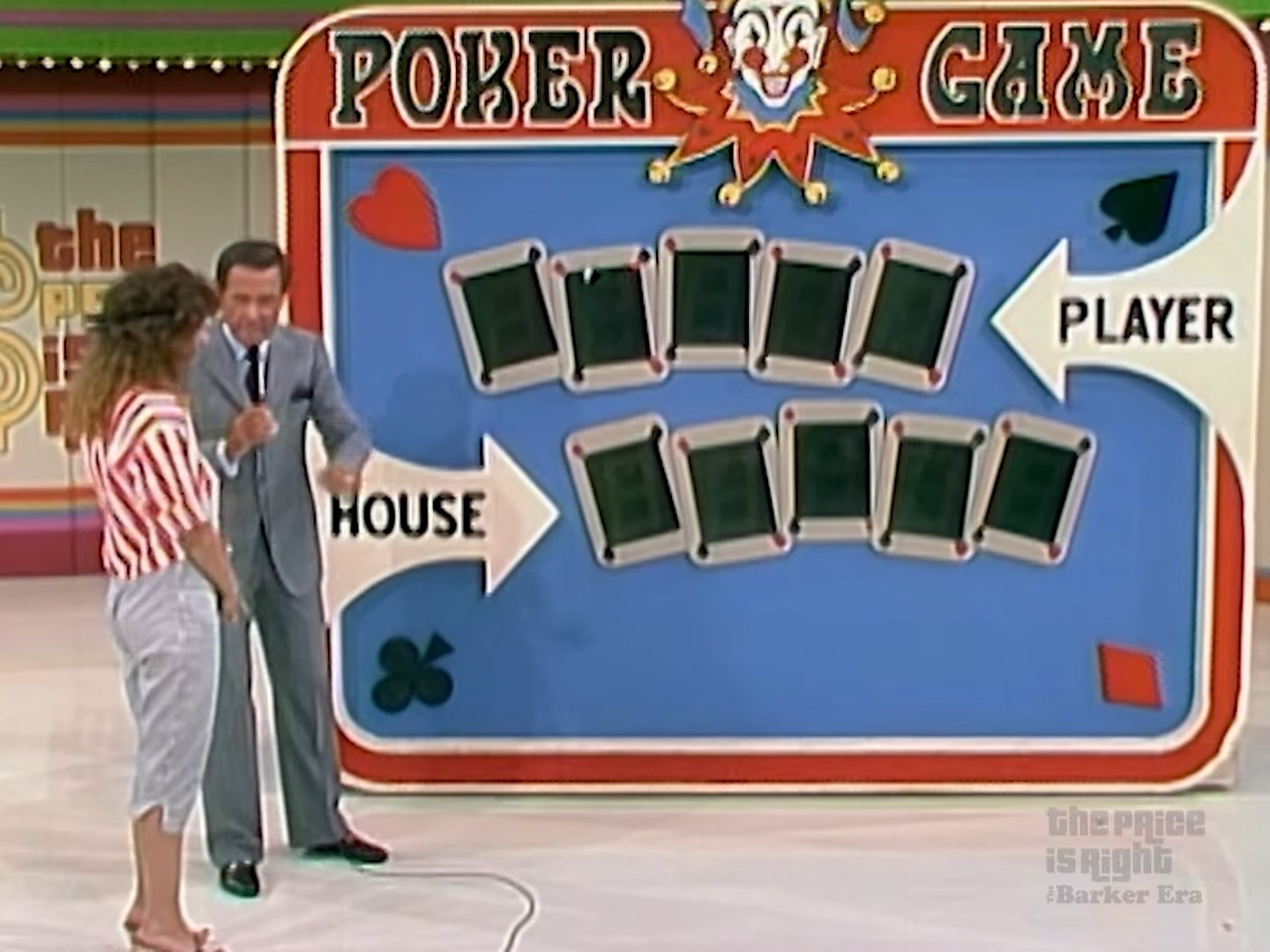 A scene from the game show 'The Price is Right,' featuring the 'Poker Game' setup. A host in a gray suit talks to a contestant, with a colorful game board displaying two categories labeled 'HOUSE' and 'PLAYER' and several covered cards.