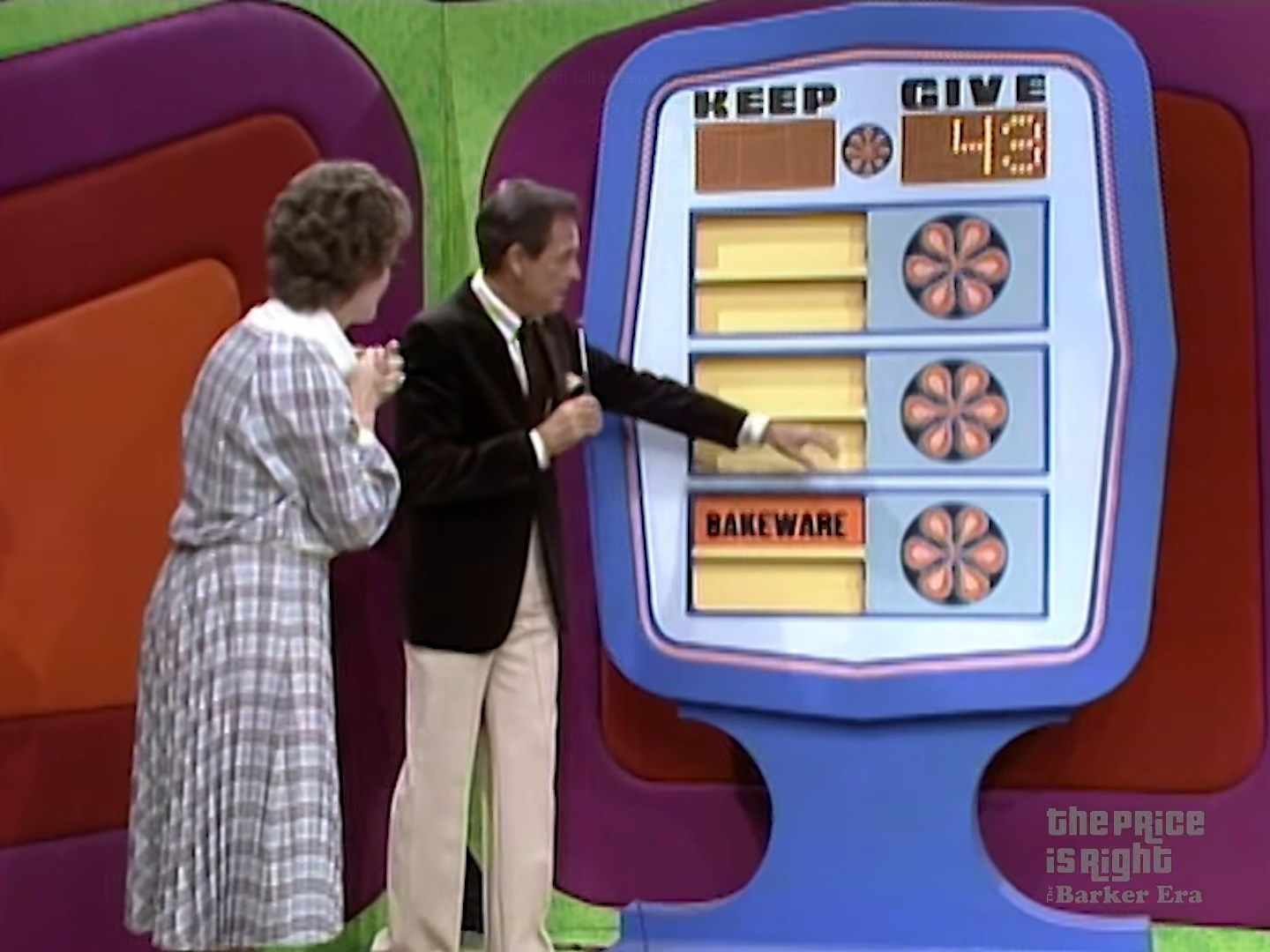 A scene from The Price is Right game show featuring a contestant and the host interacting with the 'Give or Keep' game board. The board displays the words 'KEEP' and 'GIVE' with numbers next to them, and the host points at a prize labeled 'BAKEWARE'.