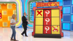 A player and host interacting with the 'Secret X' game on The Price is Right, featuring a board with red crosses and question marks in a colorful studio setting.