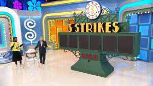 A game show set featuring the '5 Strikes' game display with large lettering, vibrant colors, and a host interacting with a contestant.