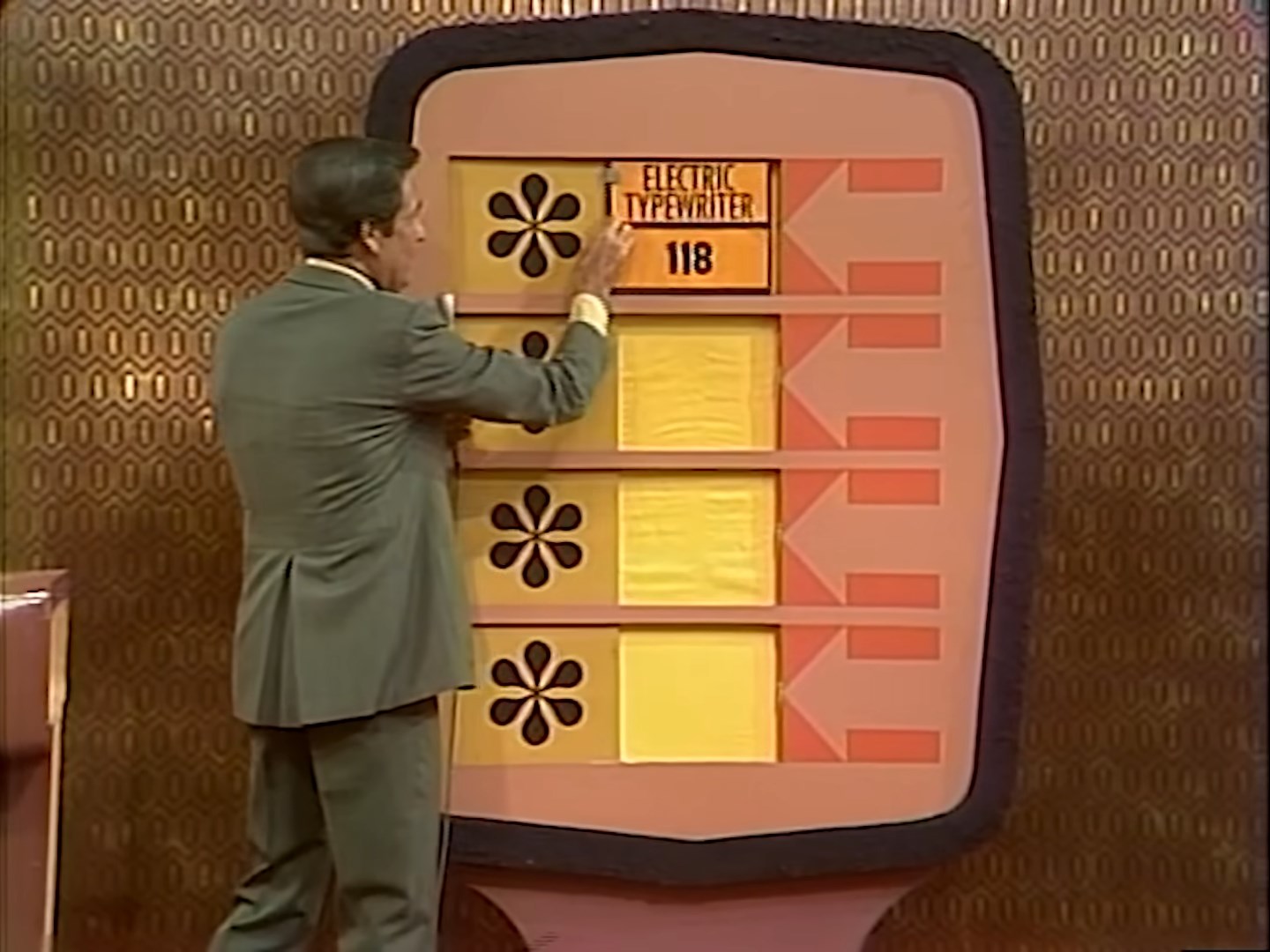 Bob Barker points to a Bonus Game board displaying an electric typewriter with a price tag of 8, part of an episode of The Price is Right's premiere episode in 1972.