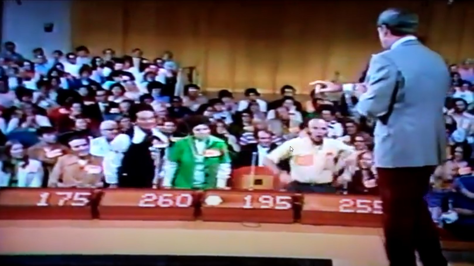 A scene from the game show The Price is Right featuring contestants at podiums bidding on a prize, with an enthusiastic audience in the background.