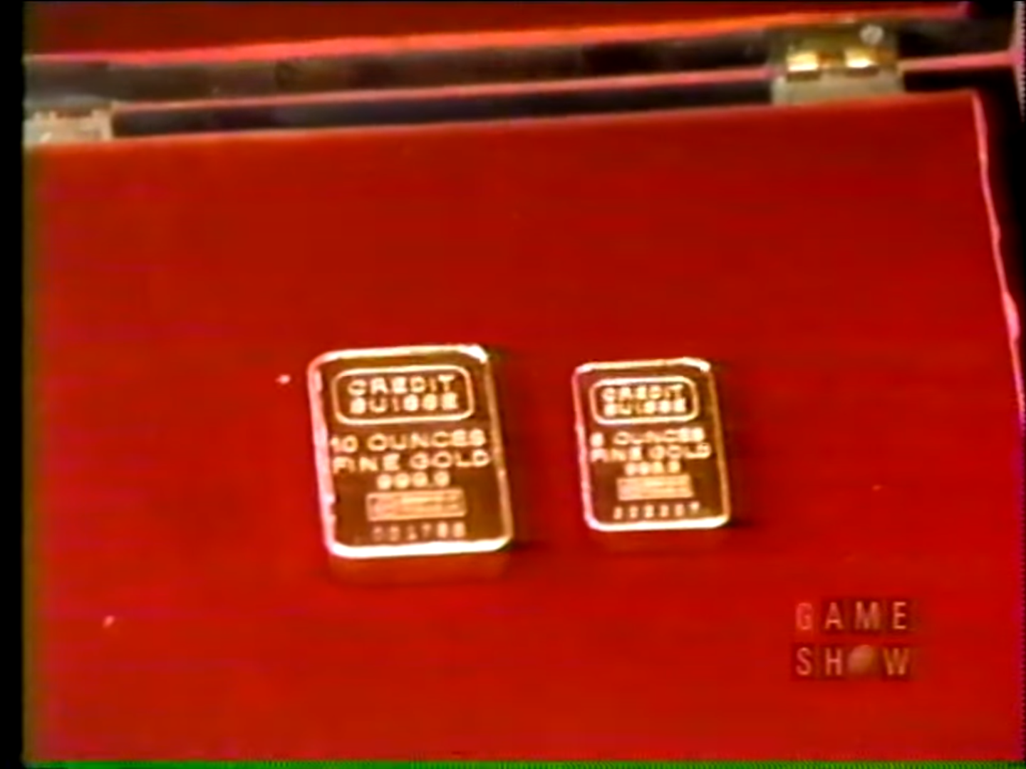 Two gold bars resting on a red velvet surface, one weighing 10 ounces and the other 8 ounces, both marked with 'Credit Suisse'.