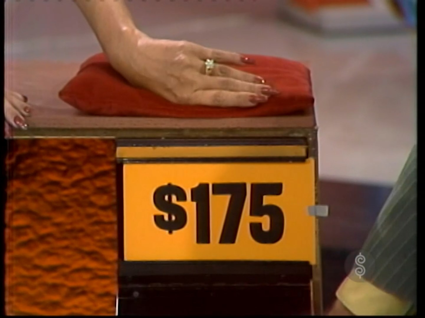 5 price tag displayed with a hand resting on a red cloth covering a prize.