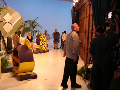 Backstage view of a TV studio set during the Season 34 premiere, featuring game show props and crew members preparing for the show.