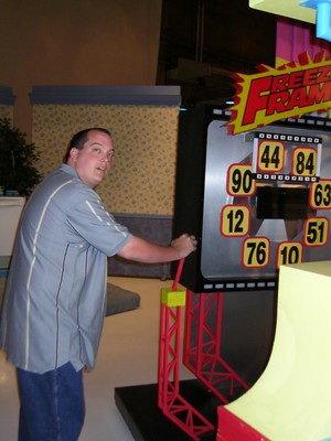 A person interacting with a game show display titled 'Freezing Frame,' with colorful numbers and graphics in a studio setting.