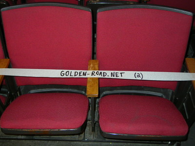 Two red theater seats with a white sign reading 'GOLDEN-ROAD.NET (2)' placed across the armrest.