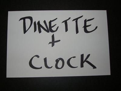 A sign displaying the words 'DINETTE + CLOCK' in large, handwritten letters.