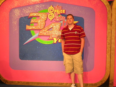 A person standing in front of a colorful backdrop celebrating the 34th season of 'The Price is Right,' featuring the show's logo.