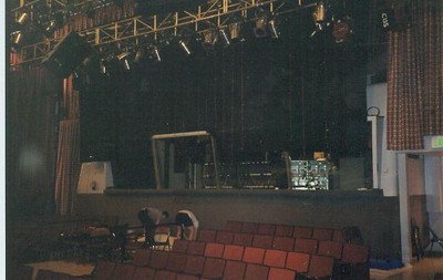 Interior view of a studio with rows of red seats and lighting equipment hanging from the ceiling.