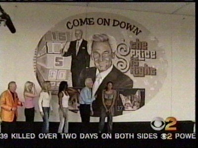 A mural depicting the iconic phrase 'Come On Down' alongside a representation of a game show host and contestants in front of a colorful backdrop from 'The Price is Right'.