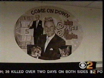 A mural depicting a cheerful host alongside a dog, with the phrase 'Come On Down' and a colorful game wheel, referencing the game show 'The Price Is Right'.