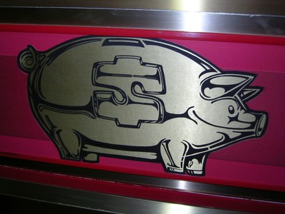 A metallic representation of a piggy bank with a dollar sign on its side, displayed against a red background.