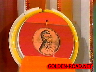 A colorful display of an oversized penny on a game board from the Penny Ante segment of a game show.