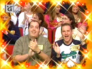 Two excited audience members clapping and smiling, surrounded by a cheering crowd during a special moment on the show.